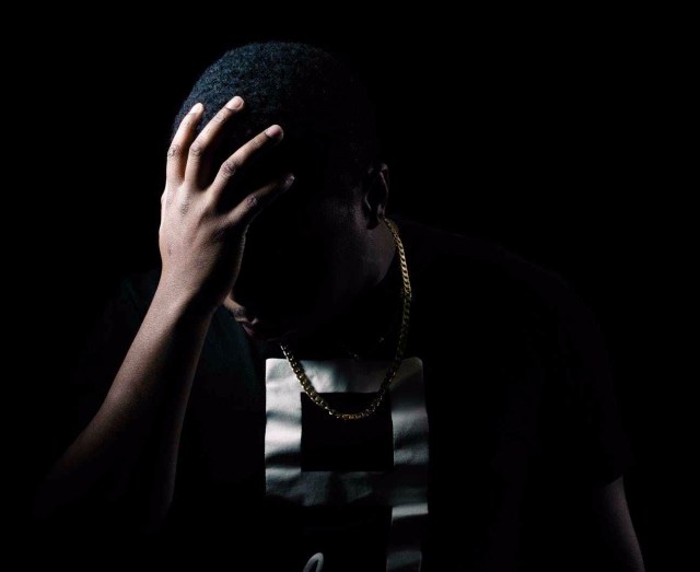 photo of man with hand on his head in the dark